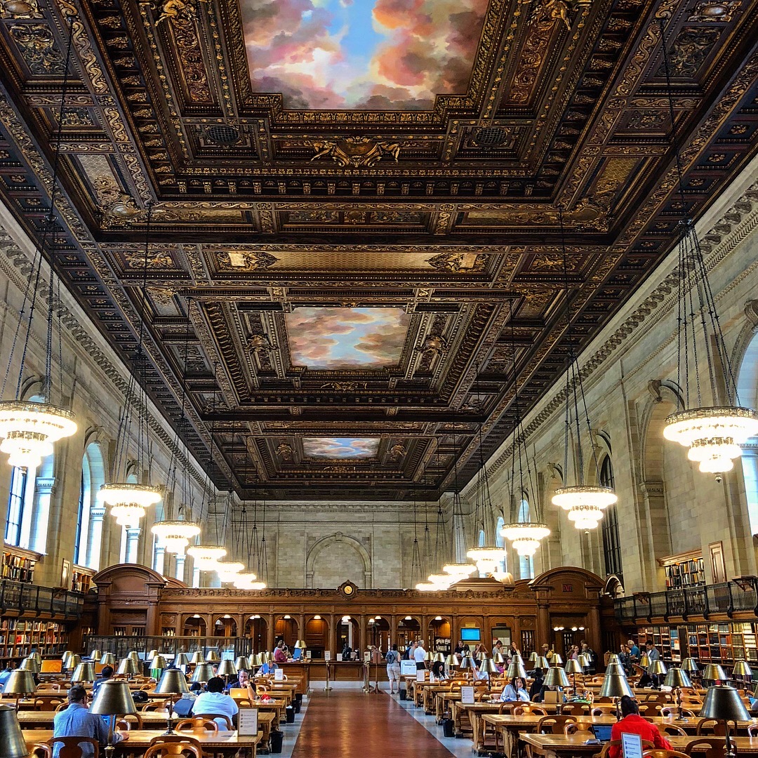 A quiet library reading room with long study tables